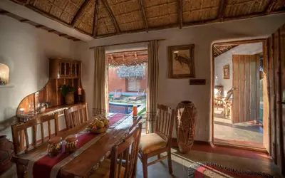a dining room with a table and chairs and a window at Evolve Back Kabini in Begūr