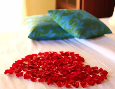 a pile of red rose petals on a bed at Elysium Garden in Munnar