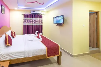 a bedroom with a bed with a tv on the wall at Sree Comforts in Kushālnagar