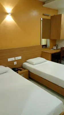 a hotel room with two beds and a kitchen at Hotel Kapilavasthu in Palakkad