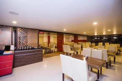 a restaurant with white chairs and tables and a bar at Hotel Kapilavasthu in Palakkad