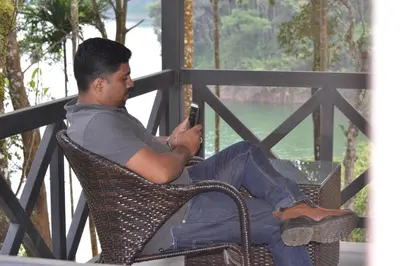 a man sitting in a chair looking at his cell phone at The Serenity Resort in Tariyod