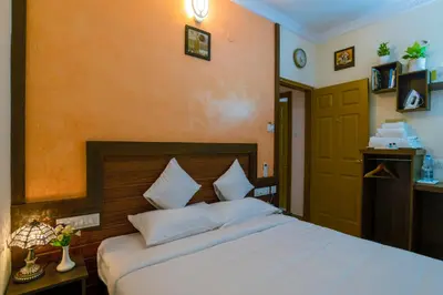 a bedroom with a large white bed and a orange wall at Blue Bell Cochin Airport Hotel in Nedumbassery
