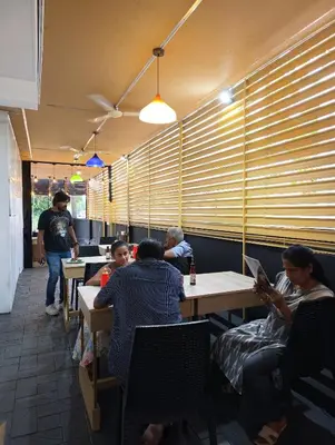 a group of people sitting at tables in a restaurant at Blue Bell Cochin Airport Hotel in Nedumbassery
