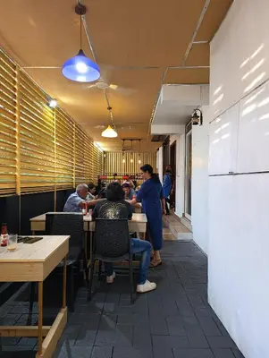 a group of people sitting at tables in a restaurant at Blue Bell Cochin Airport Hotel in Nedumbassery