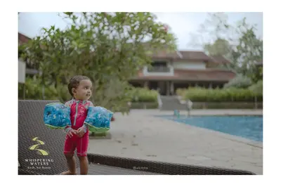 a little boy standing on a bench near a swimming pool at Whispering Waters in Malayāttūr