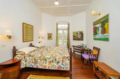 a bedroom with a bed and a desk at Neemrana's Wallwood Garden in Coonoor