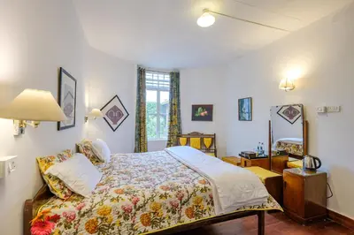 a bedroom with a bed and a mirror at Neemrana's Wallwood Garden in Coonoor
