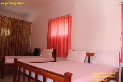 two beds in a room with red curtains at Kanthalloor Homestay Snow White Holiday Homes in Kanthalloor