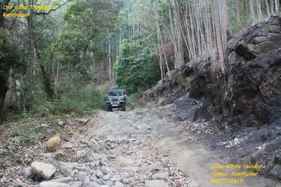 a jeep driving down a dirt road in a forest at Kanthalloor Homestay Snow White Holiday Homes in Kanthalloor