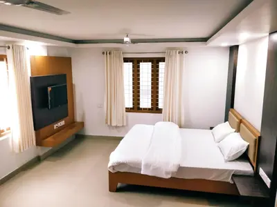 a bedroom with a bed and a flat screen tv at Prajapuri Hotel in Trichūr