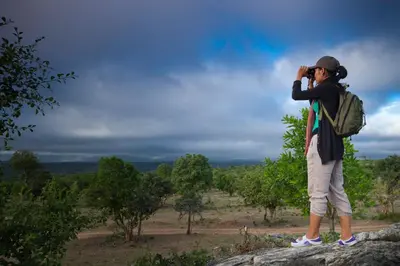 a man standing on top of a rock taking a picture at The Serai Bandipur in Bandipūr