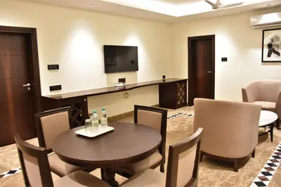 a room with a table and chairs and a tv at Poppys Vista Hotel in Thirumurugan Poondi