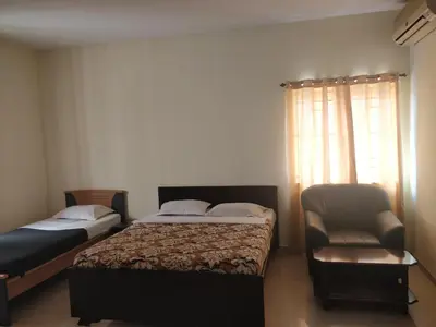 a bedroom with two beds and a chair and a window at Tulip Suites in Coimbatore
