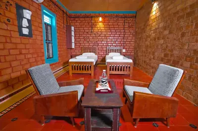 a room with chairs and tables and a brick wall at Anamala Serenity Homestay Kerala in Lakkidi