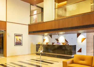a lobby with a yellow chair and people in the background at Hotel Divine Fort in Palani