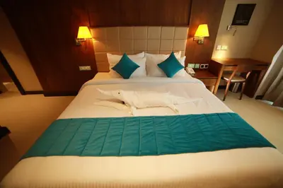 a bedroom with a large bed with blue pillows at YASH INTERNATIONAL in Kozhikode