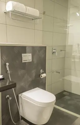 a bathroom with a toilet and a glass shower at Regency Palani by GRT Hotels in Palani