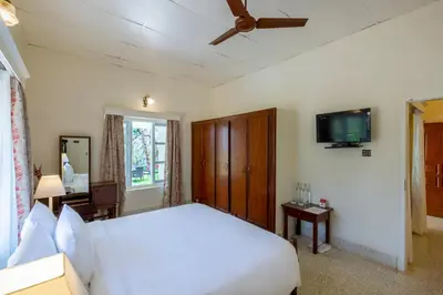a bedroom with a white bed and a flat screen tv at Ama Plantation Trails Coorg in Gonikoppal
