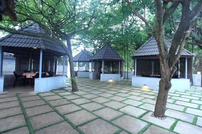 a patio with two gazebos and a tree at Victory Inn Park Residency in Kunnamkulam