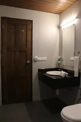 a bathroom with a toilet and a sink with a mirror at Logan Camp Ooty in Coonoor