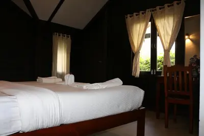 a bedroom with a bed with white sheets and a window at Logan Camp Ooty in Coonoor