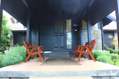 two wooden chairs sitting on the porch of a house at Logan Camp Ooty in Coonoor