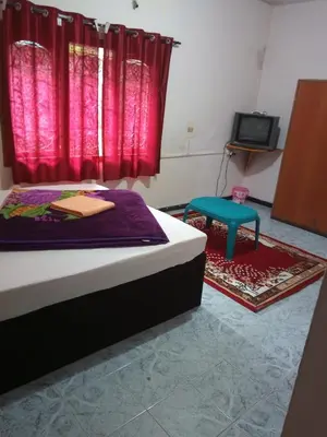 a bedroom with a bed and a tv and red curtains at Long Wood Hills Cottage in Ooty