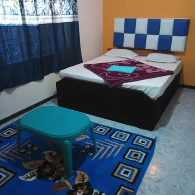 a bedroom with a bed with a blue stool on it at Long Wood Hills Cottage in Ooty