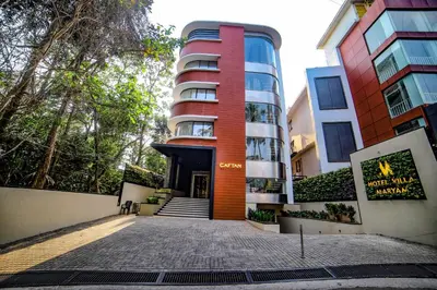 a tall building with a red at Hotel Villa Maryam in Kozhikode