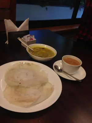 a table with a plate of soup and a cup of coffee at Hotel Villa Maryam in Kozhikode