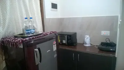 a small kitchen with a refrigerator and a microwave at RAI COTTAGE @ Coorg ,Suntikoppa in Suntikoppa
