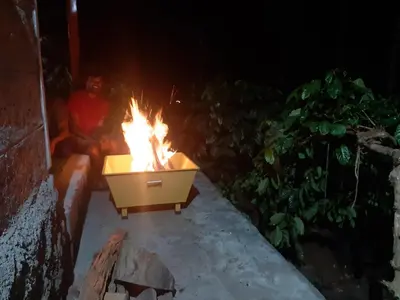 a fire in a wheelbarrow on a patio at night at RAI COTTAGE @ Coorg ,Suntikoppa in Suntikoppa