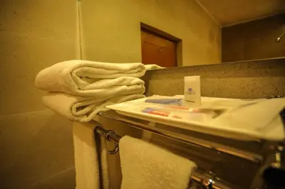 a bathroom with a sink and a mirror and towels at La Montana by TGI in Ooty