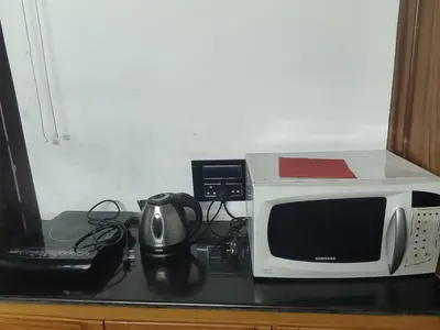 a microwave sitting on top of a counter next to a laptop at Kunnampath Heritage Nalukettu in Trichūr