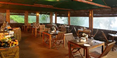 a restaurant with wooden tables and chairs and windows at Nature Zone Jungle Resort- Experience the Wilderness & Adventure in Munnar