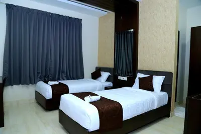 two beds in a hotel room with black curtains at MAZUS INN in Vythiri