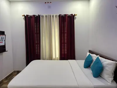 a bed with two blue pillows in a bedroom at Deluxe Residency in Kalpetta