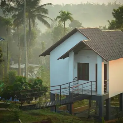 a small white house with a gambrel roof at Le Eden Premium Wayanad Pool Resort in Sultan Bathery