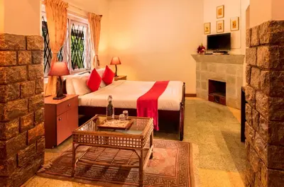 a bedroom with a bed and a fireplace at Teanest by Nature Resorts and Stays in Coonoor