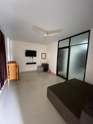 a living room with a bed and a flat screen tv at Town Hub in Valāncheri