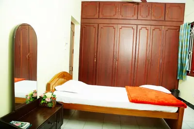 a bedroom with a bed and a large wooden cabinet at ZuriEL Suite GUEST HOUSE in Coimbatore