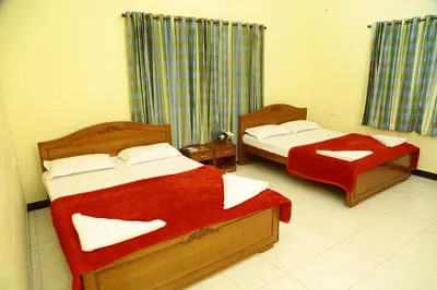 a bedroom with two beds with red sheets at ZuriEL Suite GUEST HOUSE in Coimbatore