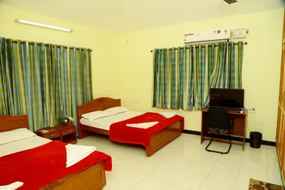a bedroom with two beds and a desk and a television at ZuriEL Suite GUEST HOUSE in Coimbatore
