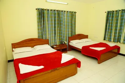 a bedroom with two beds with red sheets at ZuriEL Suite GUEST HOUSE in Coimbatore
