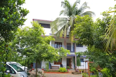 a white building with trees in front of it at Monsoon Apartments in Kannur