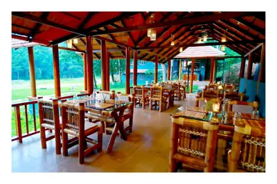 a restaurant with wooden tables and chairs in a room at Vayal Veedu in Muthanga