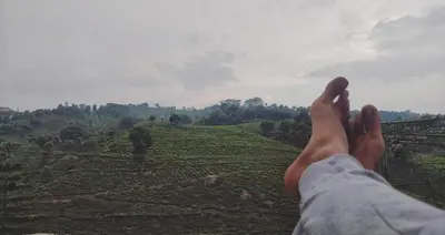 a person holding their feet up on top of a field at The Door to Nirvana Backpackers Hostel Kotagiri in Kotagiri