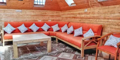 a red couch in a room with two chairs and a table at The Door to Nirvana Backpackers Hostel Kotagiri in Kotagiri