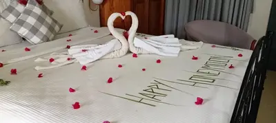 two flamingos sitting on top of a bed with roses at The Realm in Coonoor